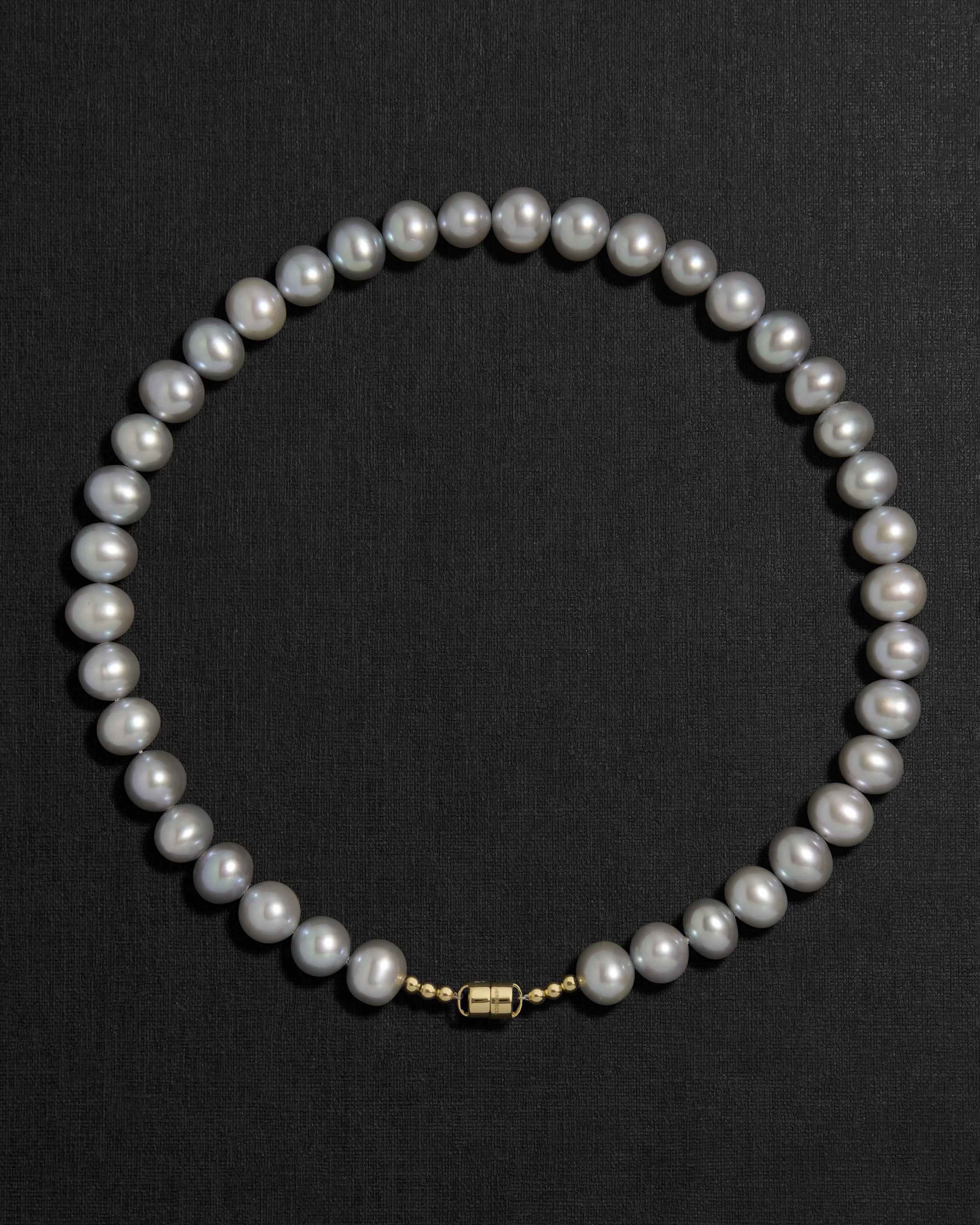 Grey pearl necklace with a 18K gold clasp on a black background