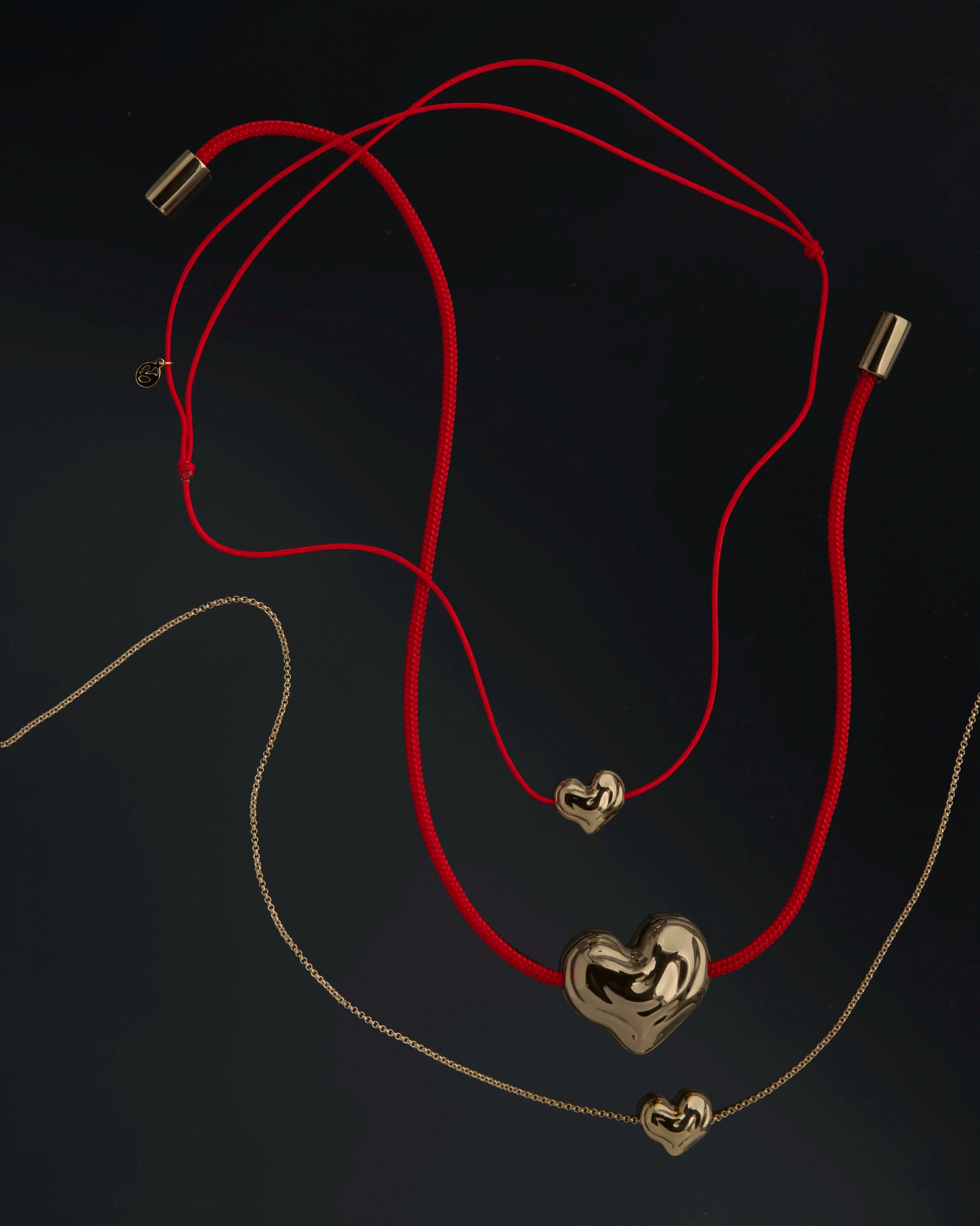 Heart-shaped 18K gold pendants on a black background