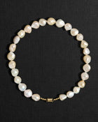 Ivory pearl necklace with a 18K gold clasp on a black background