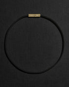 Black cord necklace with a 18K gold clasp on a black background