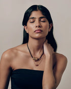 Model wearing 18K gold black cord necklace with a 18K gold heart-shaped pendant and mini 18K gold chain heart-shaped pendant