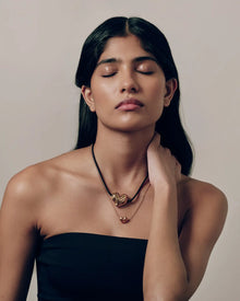 Model wearing 18K gold black cord necklace with a 18K gold heart-shaped pendant and mini 18K gold chain heart-shaped pendant