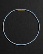 Blue cord necklace with a 18K gold clasp on a black background