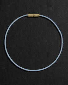 Blue cord necklace with a 18K gold clasp on a black background