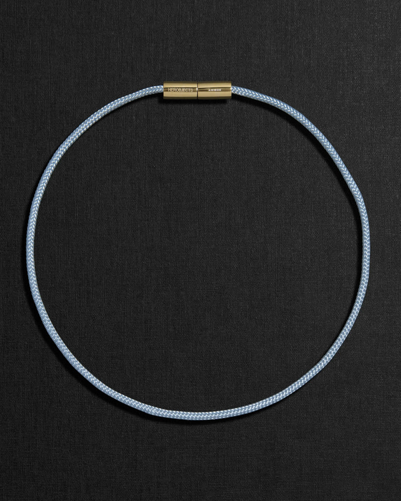 Blue cord necklace with a 18K gold clasp on a black background