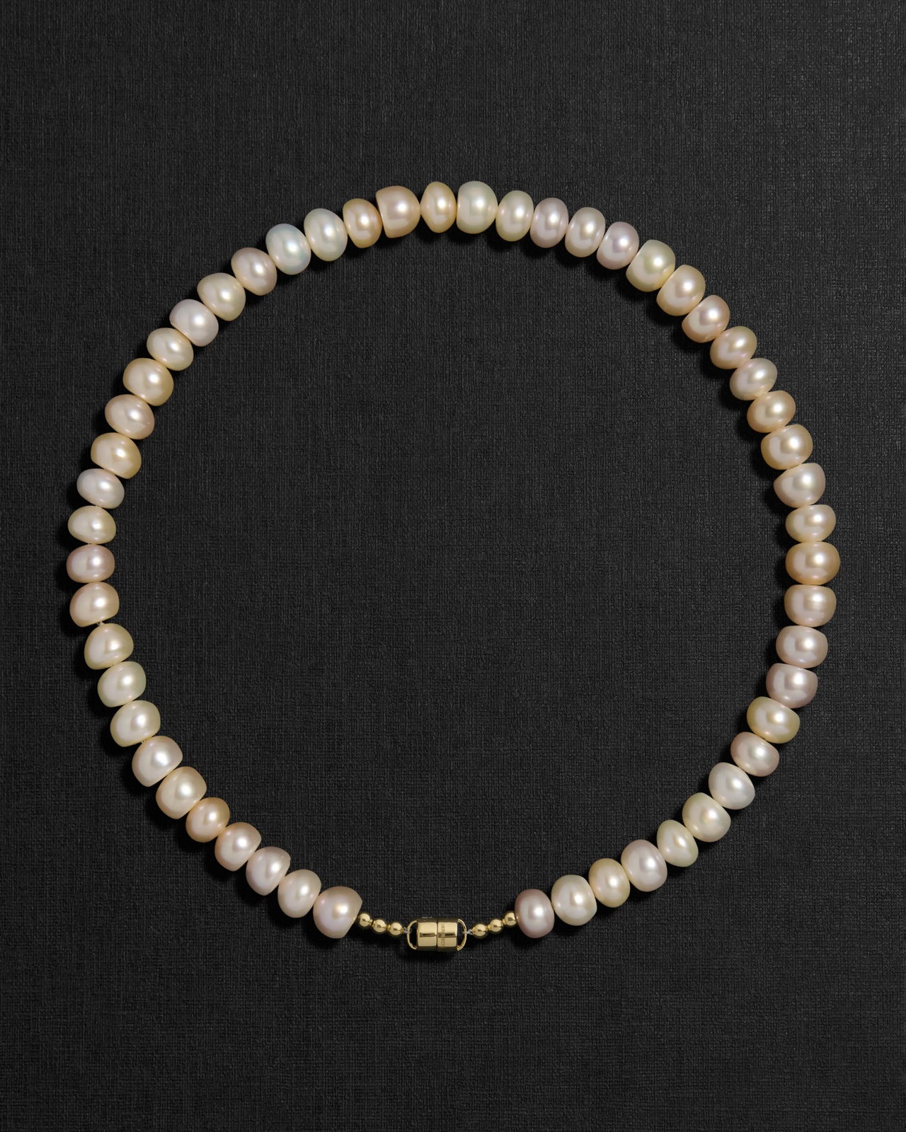 Blush pearl necklace with a 18K gold  clasp on a black background