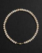 Blush pearl necklace with a 18K gold  clasp on a black background