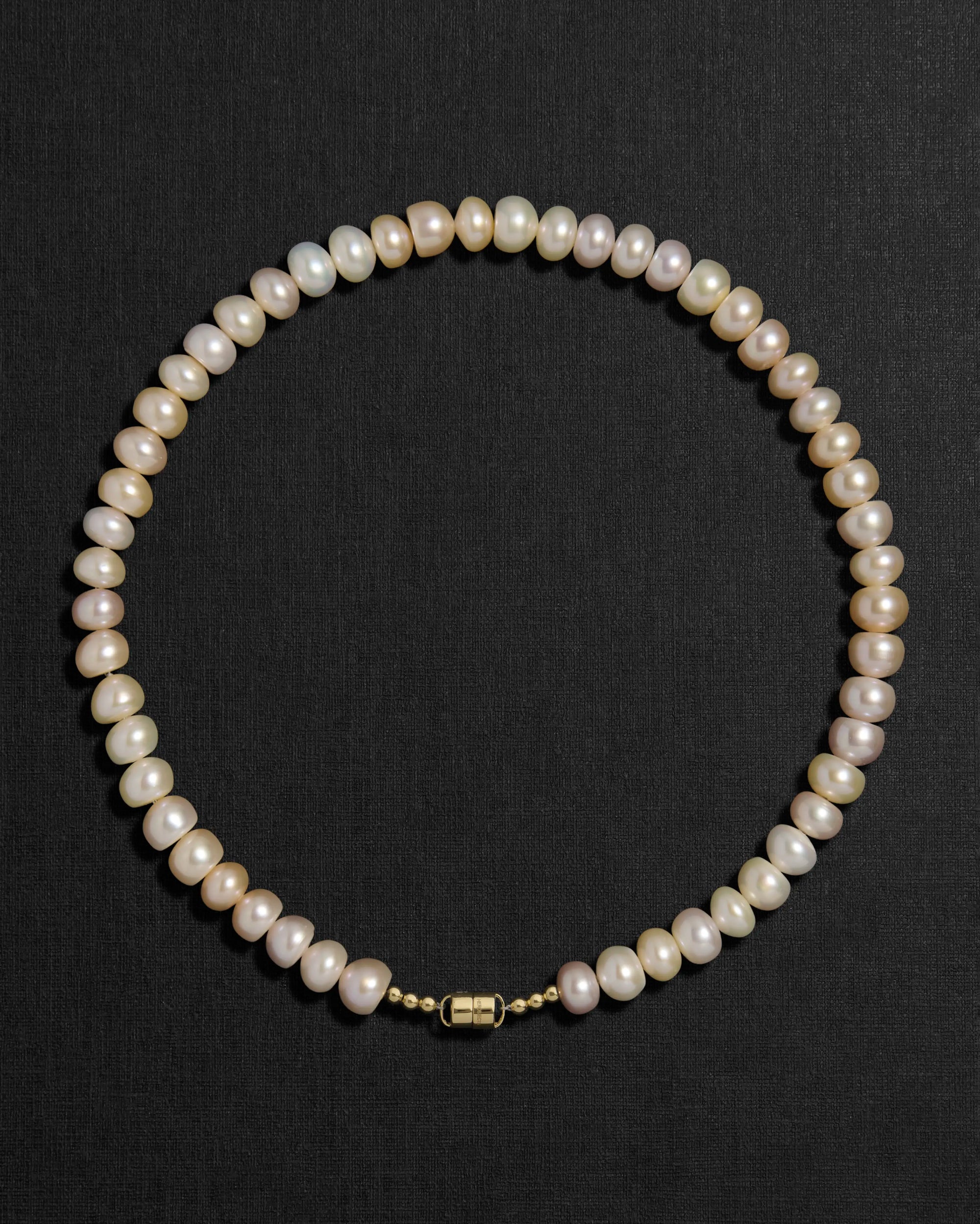 Blush pearl necklace with a 18K gold  clasp on a black background