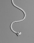 18K gold blush pearl necklace with a heart-shaped 18K gold pendant on a grey background