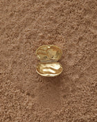 Opened 18K Gold Hero Desert pendant on a sand
