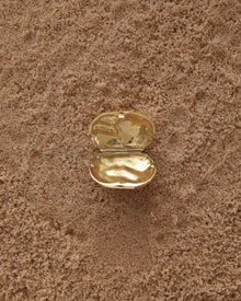 Opened 18K Gold Hero Desert pendant on a sand