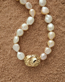 18K Gold Hero Desert pendant and 18K Gold large ivory baroque pearl on a sand