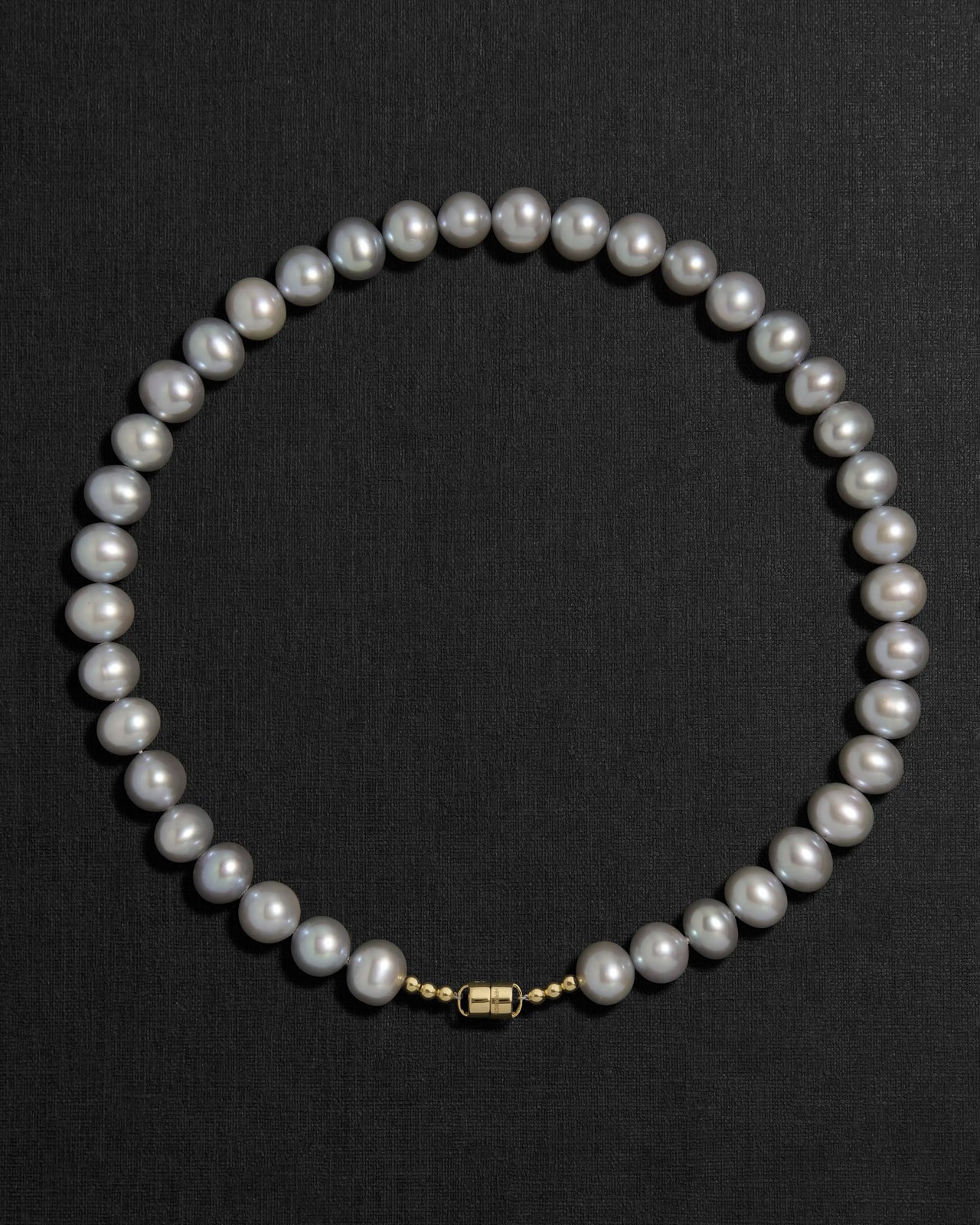 Grey pearl necklace with a 18K gold clasp on a black background