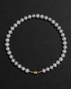 Grey pearl necklace with a 18K gold clasp on a black background