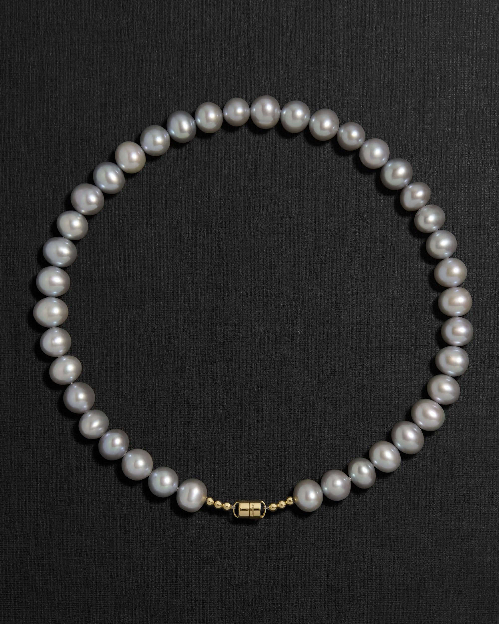 Grey pearl necklace with a 18K gold clasp on a black background