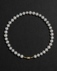 Grey pearl necklace with a 18K gold clasp on a black background