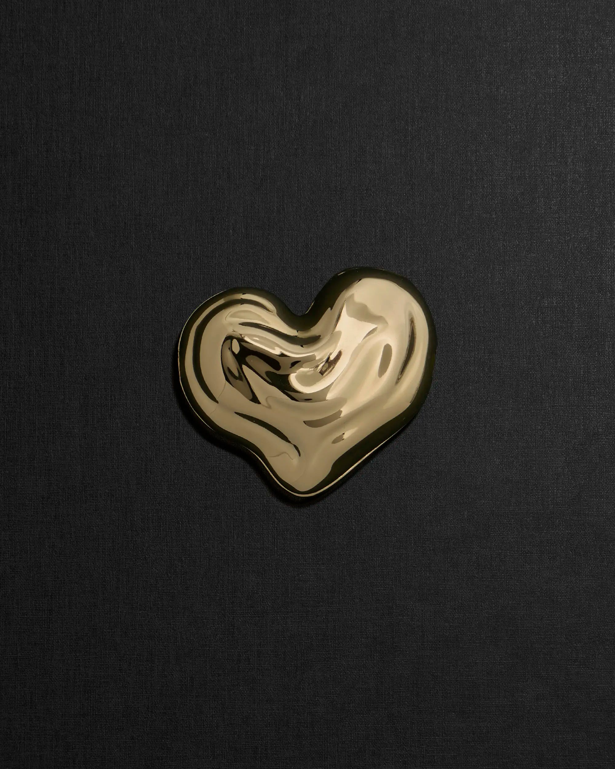 Heart-shaped 18K gold pendant on a black background