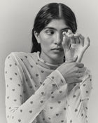 Model holding heart-shaped 18K gold pendant on a grey background