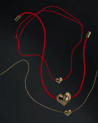 Heart-shaped 18K gold pendants on a black background