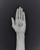 Hand holding pomegranate-shaped 18K gold pendant on a black background
