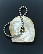 18K gold grey pearl necklace and pomegranate-shaped 18K gold pendant with a shell on a dark blue background