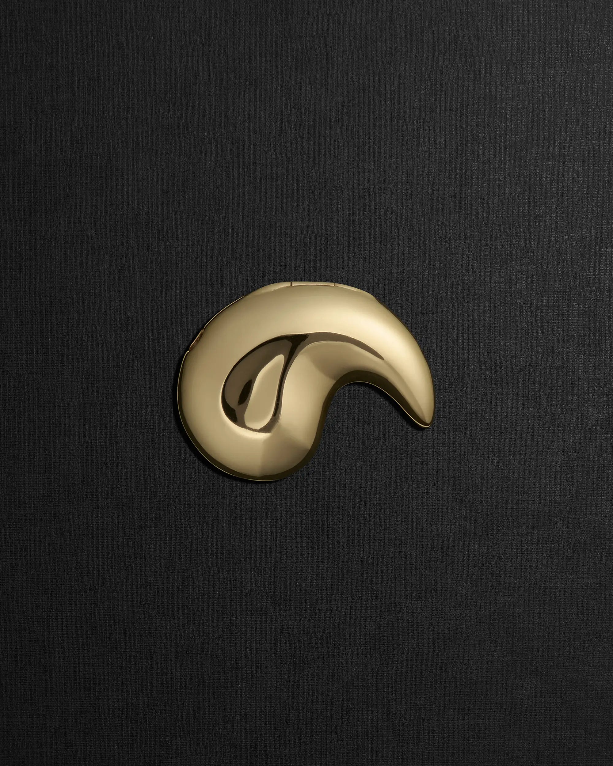 Spiral-shaped 18K gold pendant on a black background