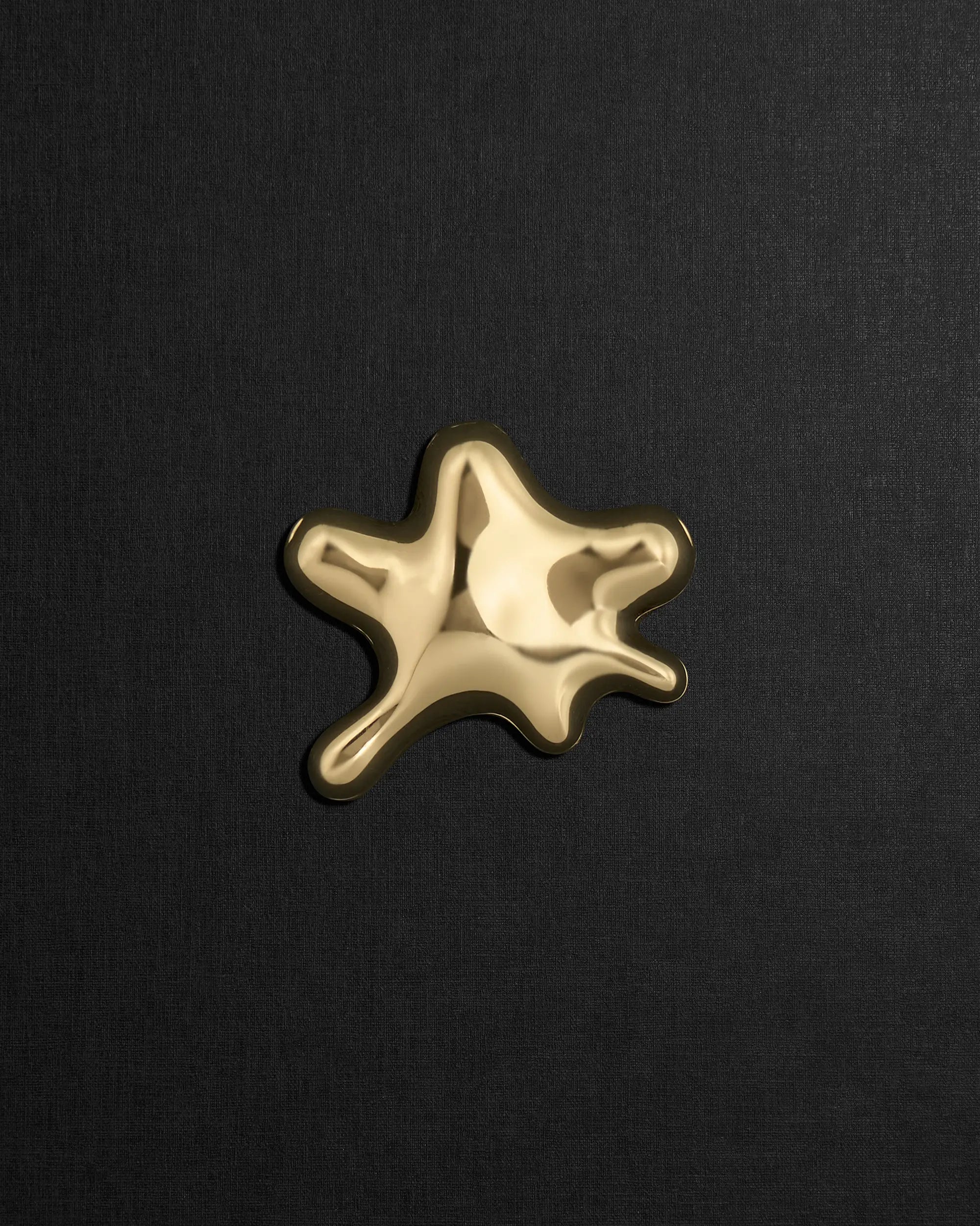 Water-shaped 18K gold pendant on a black background