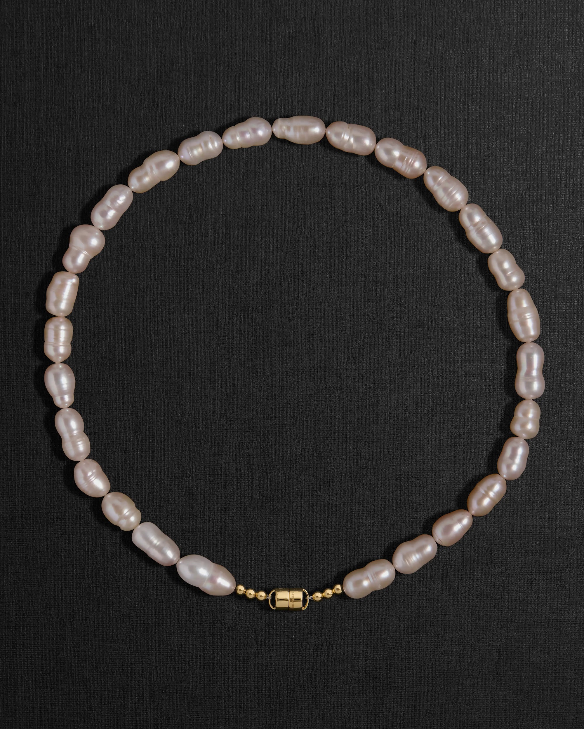 Lavender pearl necklace with a 18K gold clasp on a black background