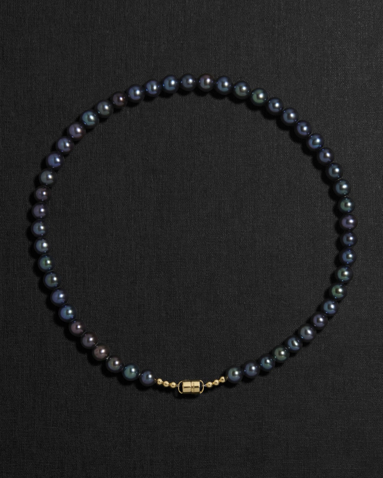 Black pearl necklace with a 18K gold  clasp on a black background
