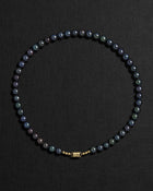 Black pearl necklace with a 18K gold  clasp on a black background