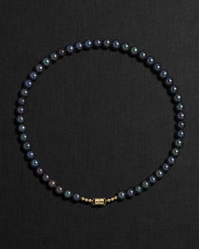 Black pearl necklace with a 18K gold  clasp on a black background