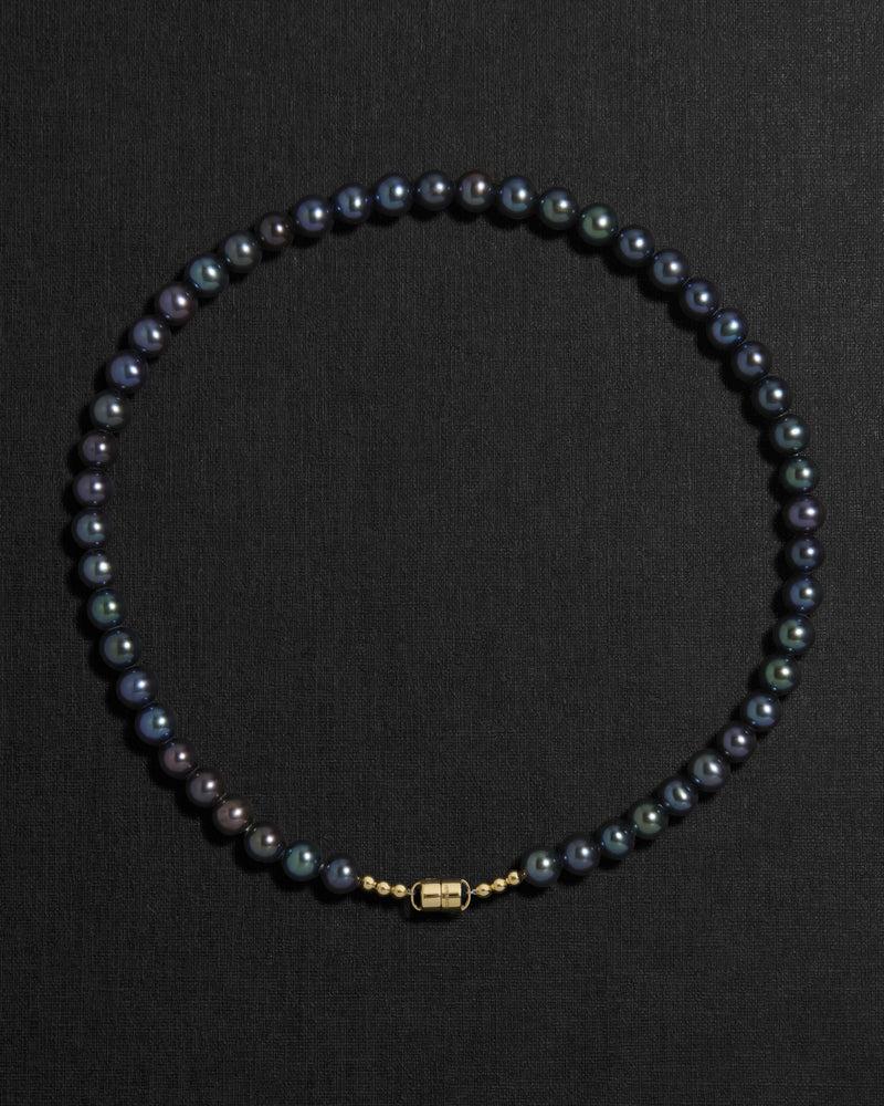 Black pearl necklace with a 18K gold  clasp on a black background