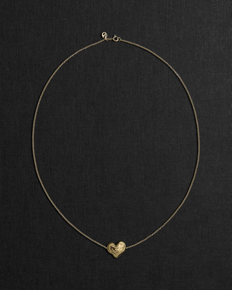 18K gold rollo chain necklace with a heart-shaped pendant on a black background