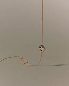 18K gold rollo chain necklace with a heart-shaped pendant on a beige background