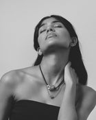 Model wearing 18K gold rollo chain necklace with a heart-shaped pendant on a grey background