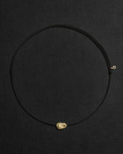 Black cord necklace with a 18K gold pomegranate-shaped pendant on a black background