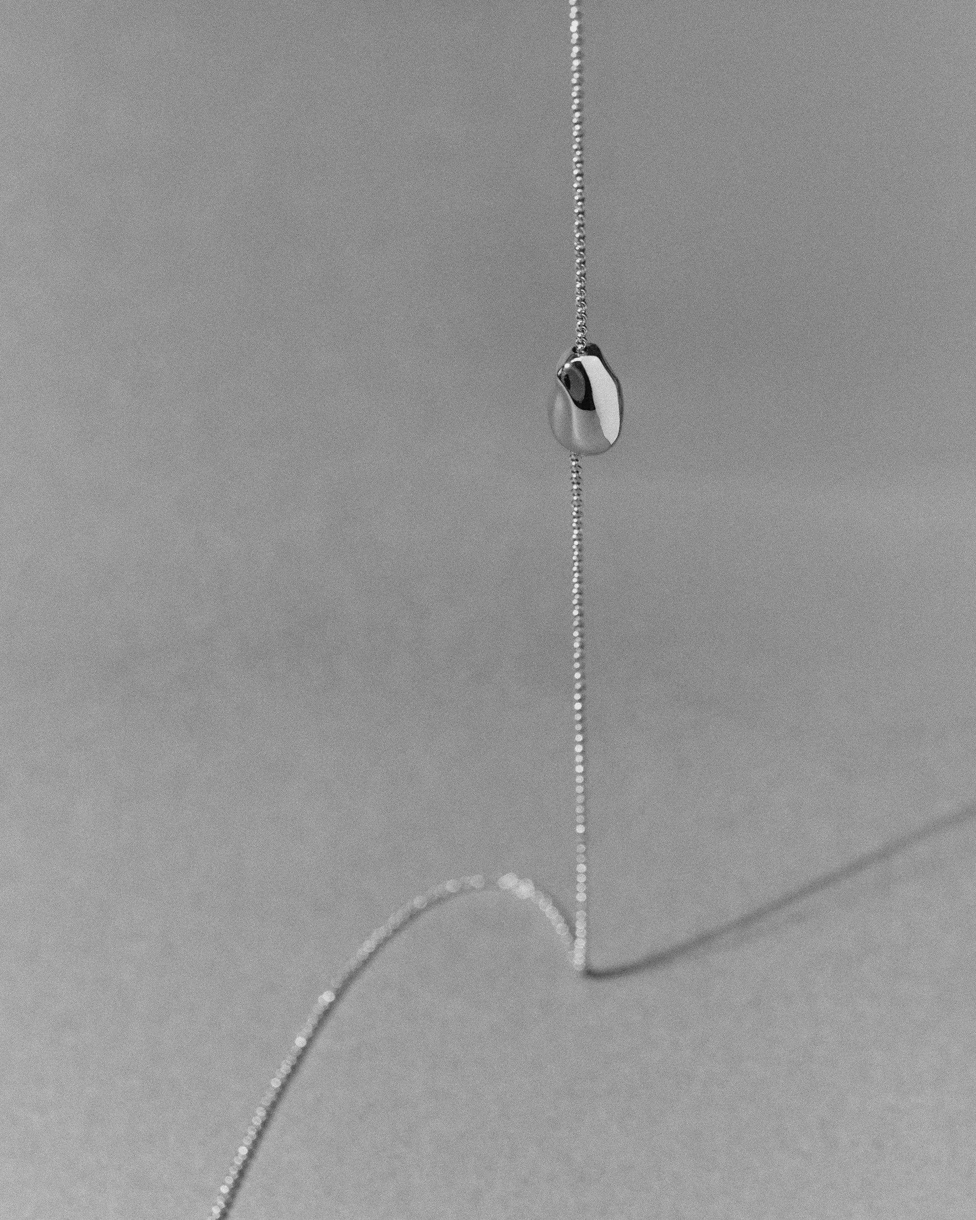 18K gold rollo chain necklace with a pomegranate-shaped pendant on a grey background