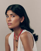 Model wears 18K Gold Mini Pomegranate on a red cord necklace, 18K Gold red cord necklace with 18K Gold Hero Pomegranate pendant, and 18K Gold Mini Pomegranate spinner necklace.