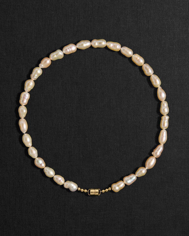 Peach pearl necklace with a 18K gold clasp on a black background