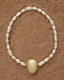 18K Gold Hero Pebble pendant and 18K Gold Freshwater pearl in Peach on a sand