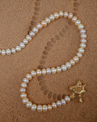18K Gold Hero Water pendant and 18K Gold Freshwater pearl in Blush on a sand