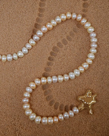 18K Gold Hero Water pendant and 18K Gold Freshwater pearl in Blush on a sand