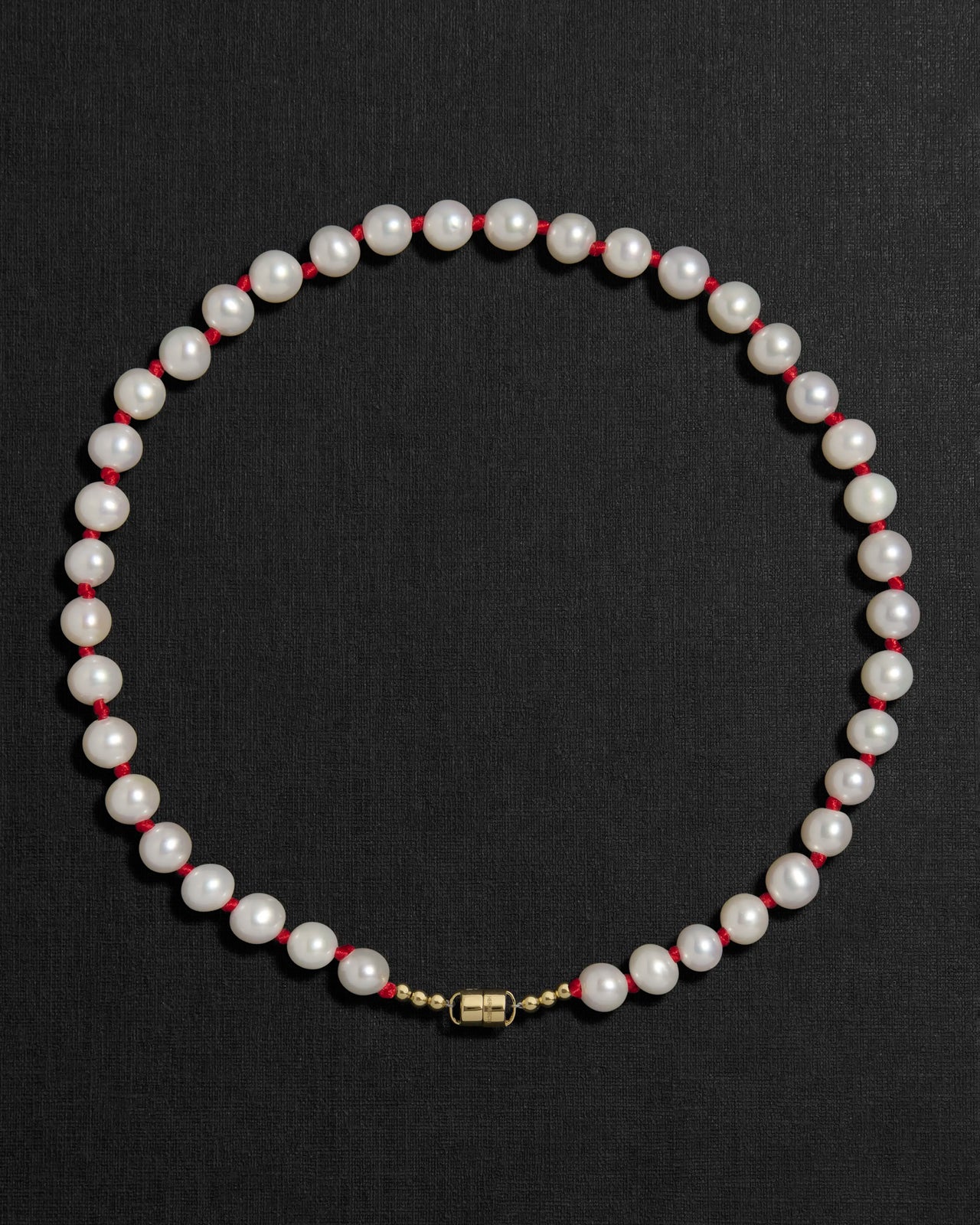 Ivory pearl and red knots necklace with a 18K gold clasp on a black background
