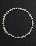 Ivory pearl and red knots necklace with a 18K gold clasp on a black background
