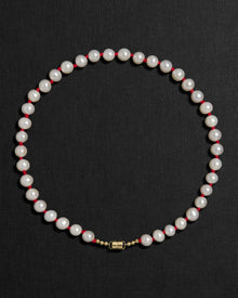 Ivory pearl and red knots necklace with a 18K gold clasp on a black background