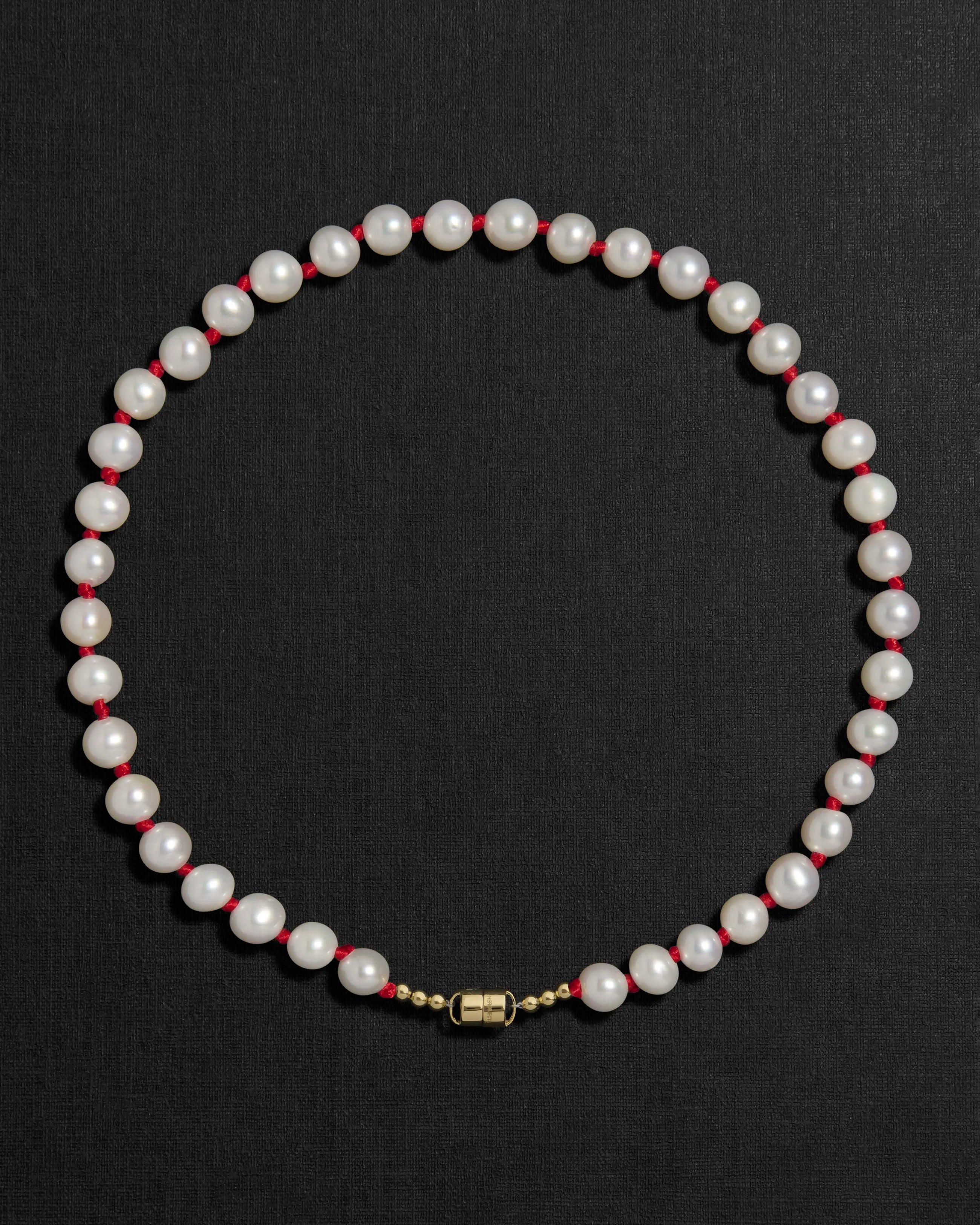 Ivory pearl and red knots necklace with a 18K gold clasp on a black background