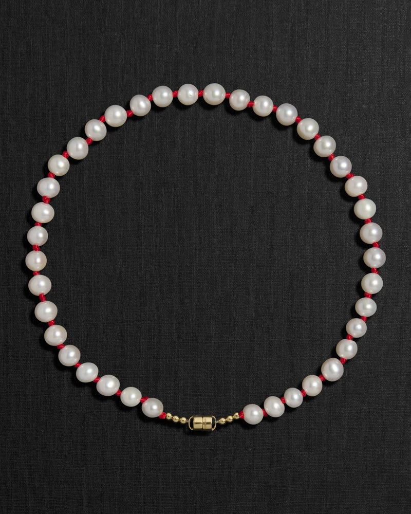 Ivory pearl and red knots necklace with a 18K gold clasp on a black background