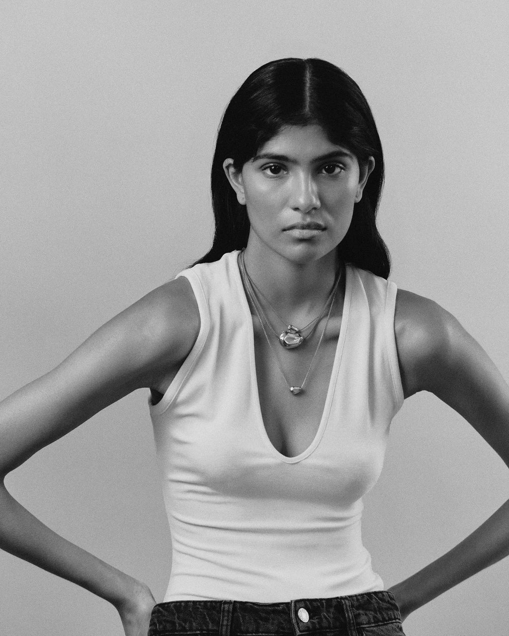Model wearing 18K red cord necklaces with 18K gold pomegranate-shaped pendants on a grey background