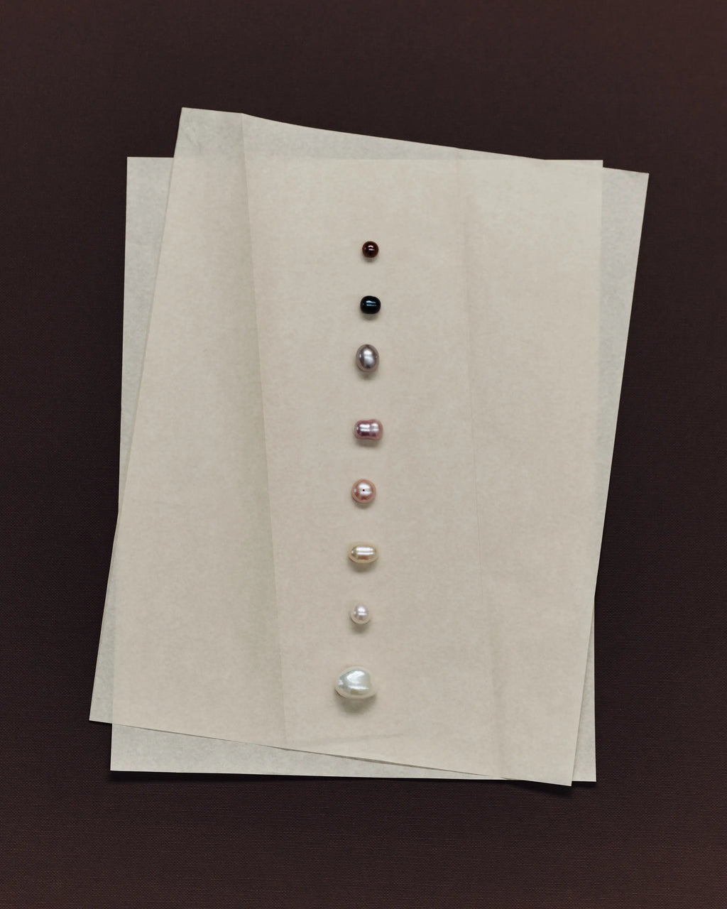 Set of pearls on a beige card against a brown background