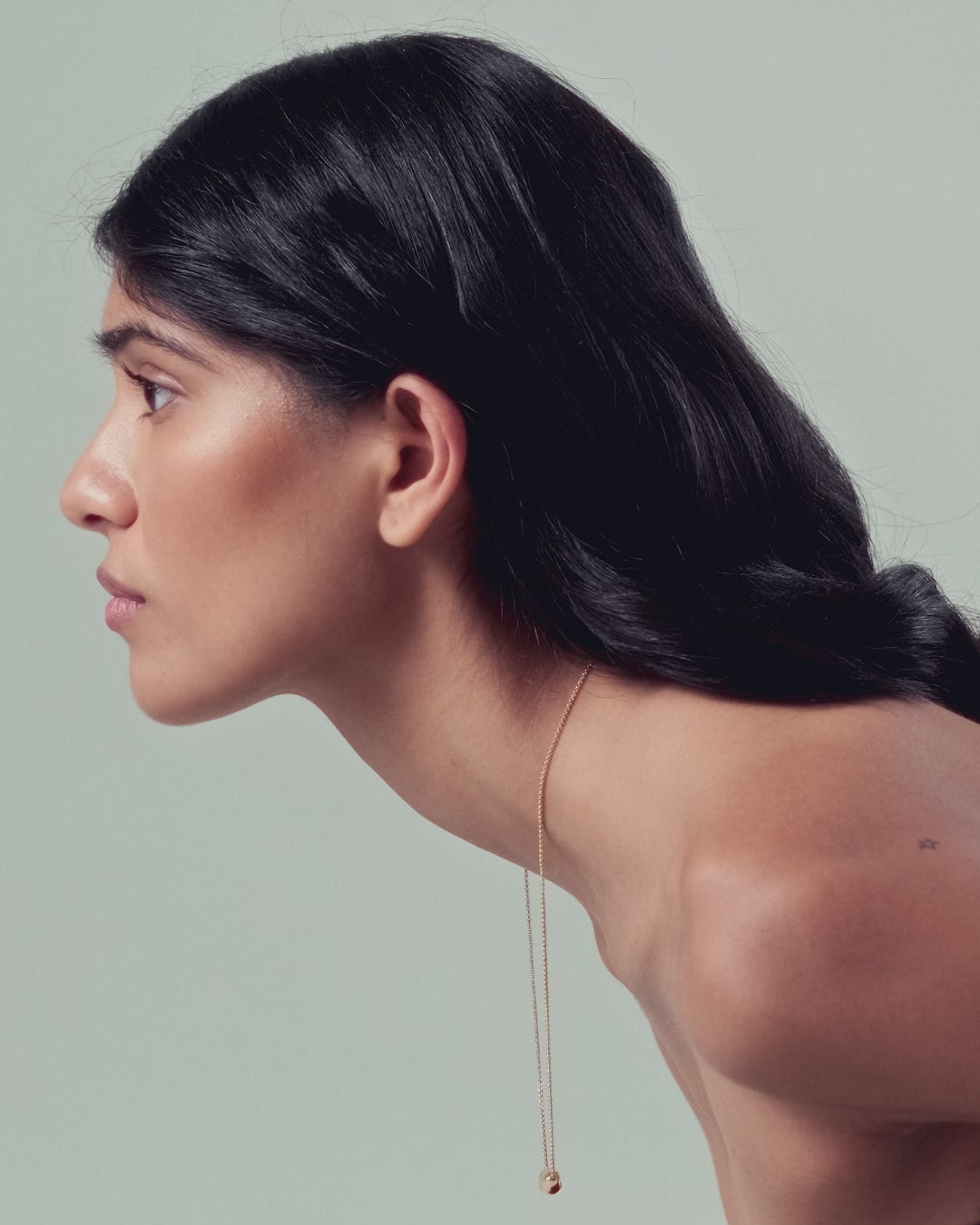 Model wearing 18K gold rollo chain necklace with a pomegranate-shaped pendant